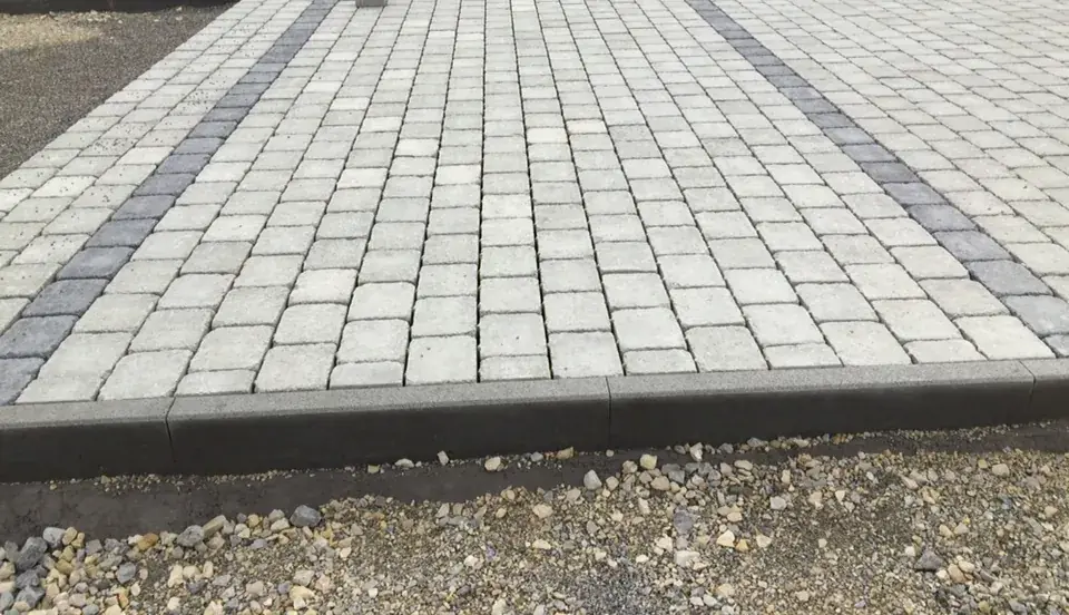 Hofeinfahrt aus hellem Betonpflaster mit anthrazitfarbenen Bändern